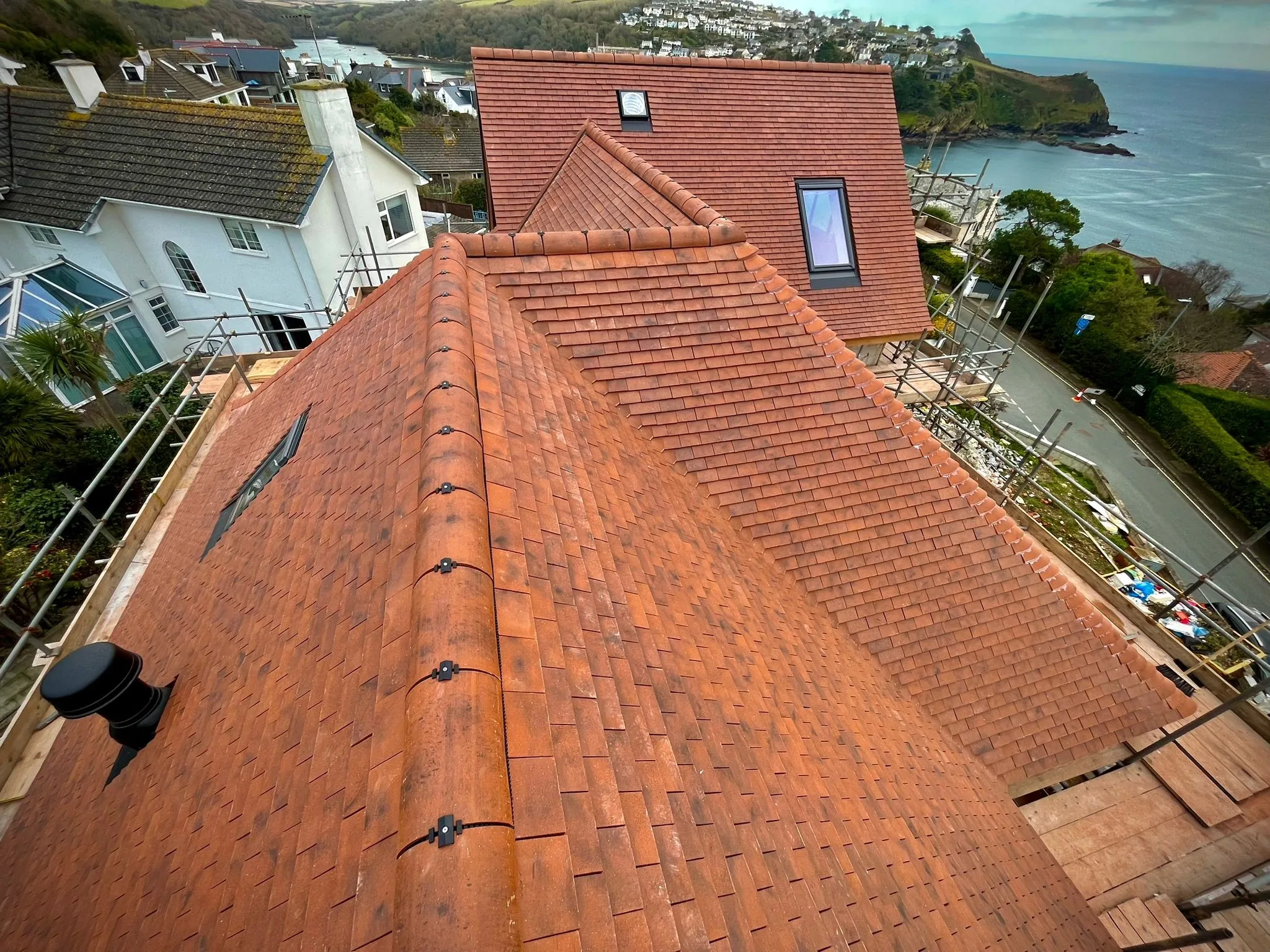 Red tile roof with two skylights overlooking a coastal village