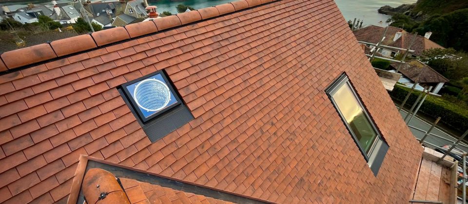 Red tile roof with two skylights overlooking a coastal village