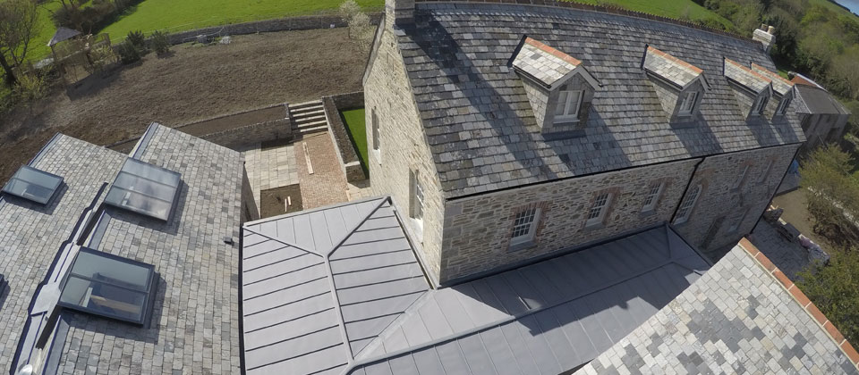 Slate roof with dormers and adjoining metal roof on a stone house